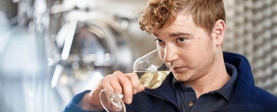 Mit einem Glas Wein in der Hand zeigt der Mann eine Mischung aus Genuss und Konzentration, während er den Wein riecht.