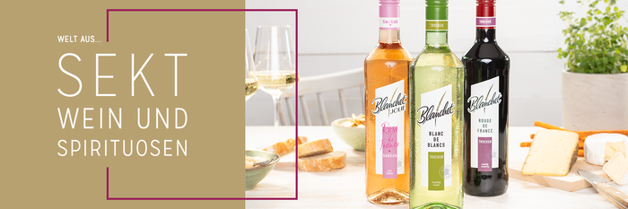 Drei Flaschen Wein von Blanchet stehen auf einem Tisch, umgeben von Käse und Brot, mit Gläsern im Hintergrund.