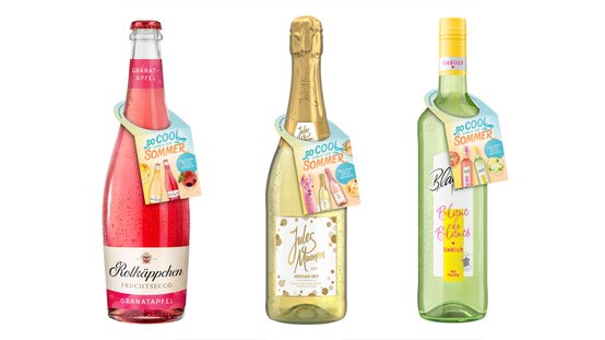 Drei Flaschen Fruchtsecco stehen nebeneinander, jede mit einem bunten Etikett, das den Sommer und fruchtige Aromen bewirbt.