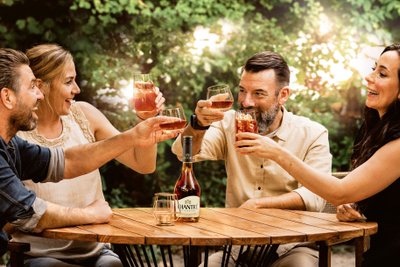 Three people clink glasses while a bottle of CHANTRÉ sits on the table, surrounded by a beautiful natural backdrop.