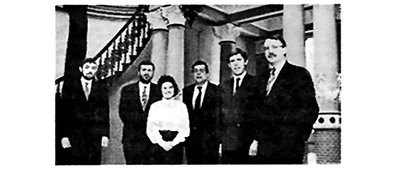  Group photo of six people in front of an elegant staircase