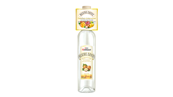 Obstillustrationen zieren das Etikett der Flasche 'Reiche Ernte', die elegant auf einem neutralen Untergrund steht.