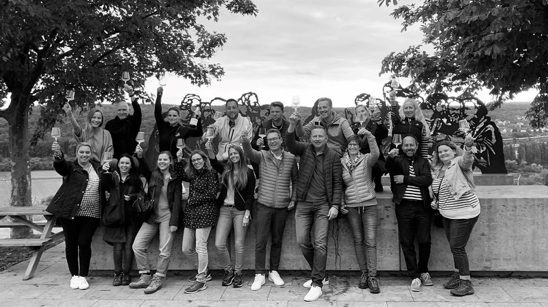 Eine Gruppe von Menschen hebt Gläser in die Luft, um einen feierlichen Moment in einer malerischen Umgebung zu zelebrieren.