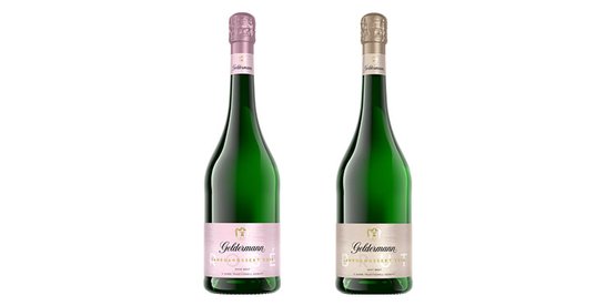 Zwei Flaschen Goldmann Sekt stehen nebeneinander, eine mit rosafarbenem Etikett und die andere mit silbernem Etikett.