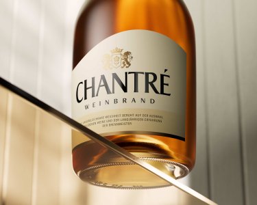 Eine elegante Flasche Chantré Weinbrand schimmert im Licht, mit einem klaren Etikett und einem goldenen Deckel.