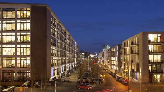 Bremen: Eine belebte Straße mit modernen Gebäuden, die abends beleuchtet sind, vermittelt eine lebendige städtische Atmosphäre.