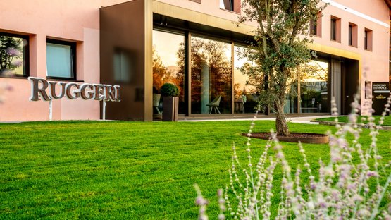 The modern façade of the building with the lettering 'Ruggeri' is surrounded by a well-kept, green lawn.