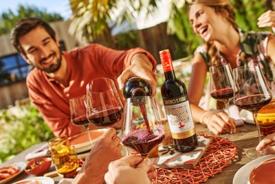 A joyful gathering outdoors where wine is poured and friends enjoy the moment with laughter and joy.