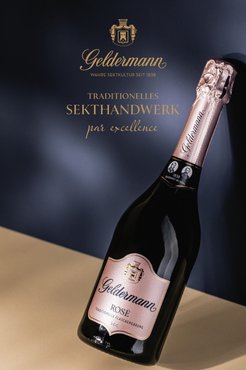 „Flasche Geldermann Rosé Sekt vor dunkelblauem Hintergrund mit goldener Schrift zu traditionellem Handwerk.“