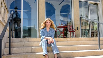 Porträtfoto Silvia Wiesner: In Jeans und schwarzen Schuhen sitzt sie auf den Stufen vor dem Pavillon der Rotkäppchen Erlebniswelt