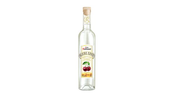 Eine klare Flasche mit einem Korken, gefüllt mit einem klaren Obstbrand, der Kirschen auf dem Etikett zeigt.