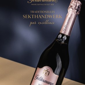 „Flasche Geldermann Rosé Sekt vor dunkelblauem Hintergrund mit goldener Schrift zu traditionellem Handwerk.“