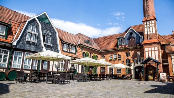 Nordhausen: Ein einladender Innenhof mit Tischen und Stühlen, umgeben von charmanten, historischen Gebäuden und Sonnenschirmen.