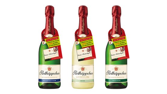 Drei Flaschen Rotkäppchen Sekt stehen nebeneinander, jede mit einem unterschiedlichen Etikett und rotem Korken.