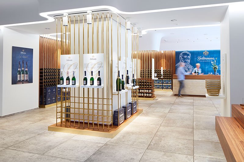 Breisach location: An elegant sales room with golden shelves displaying wine bottles and a stylish reception desk in the background.