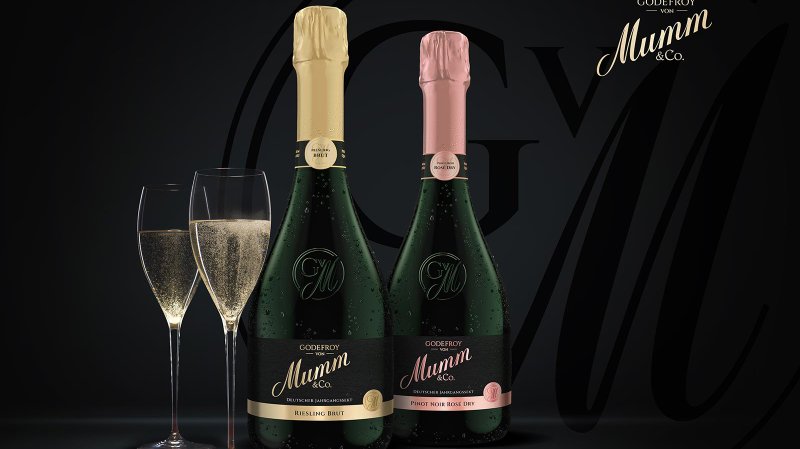 Zwei elegante Gläser mit sprudelndem Sekt stehen neben Flaschen von Mumm, die in einem stilvollen, dunklen Setting präsentiert werden.