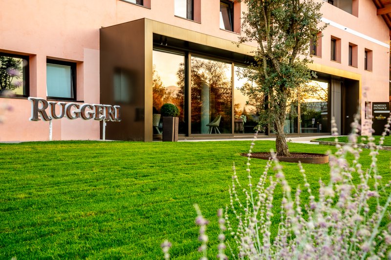 An elegant building with the 'Ruggeri' logo and a welcoming entrance door, surrounded by well-kept greenery.