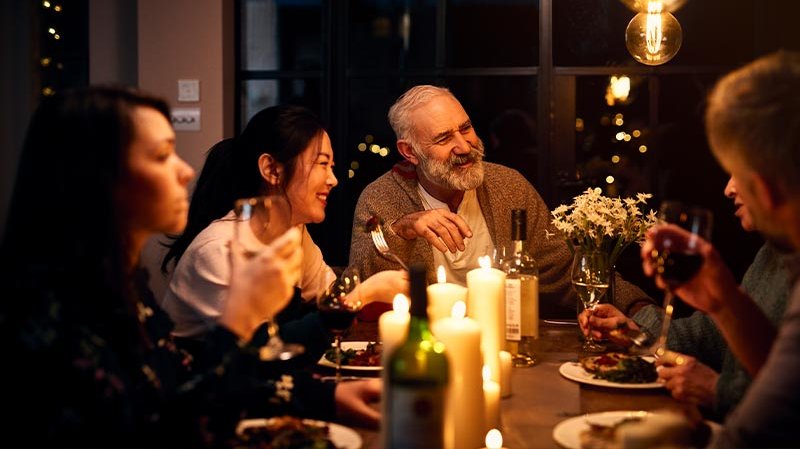 Eine fröhliche Gruppe von fünf Personen genießt ein Abendessen bei Kerzenlicht, umgeben von einer warmen, einladenden Atmosphäre.