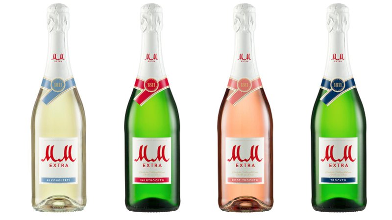 Die Flaschen zeigen eine Auswahl an Sektvarianten: alkoholfrei, halbtrocken, rosé und trocken, alle mit stilvollen Etiketten.
