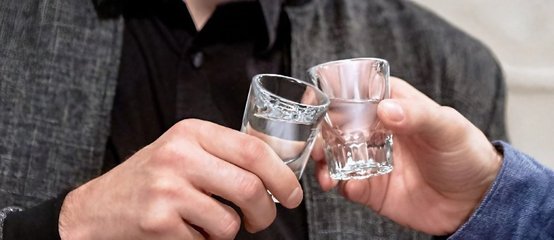 Two people clinking shot glasses