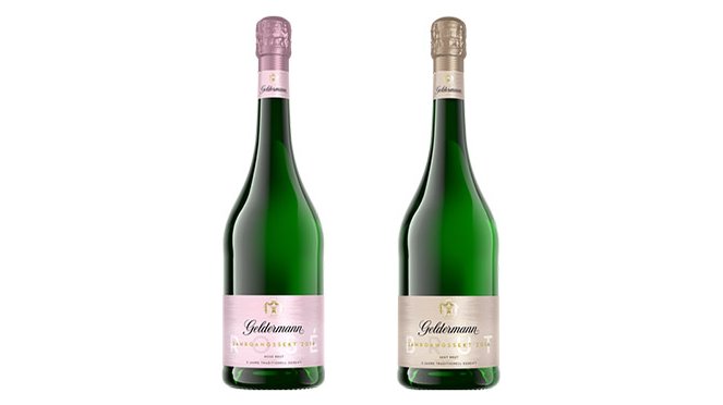 Zwei Flaschen Goldmann Sekt stehen nebeneinander, eine mit rosafarbenem Etikett und die andere mit silbernem Etikett.