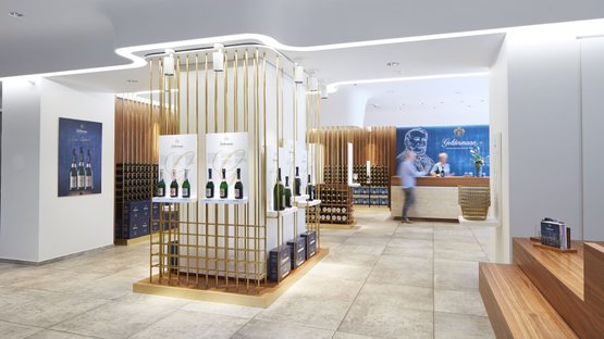 Breisach: In a bright, minimalist room, shelves are filled with champagne bottles while a customer goes to the checkout.