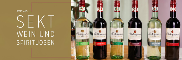 Sechs Flaschen Rotkäppchen-Wein stehen auf einem Tisch, umgeben von einer warmen, einladenden Atmosphäre.