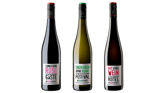 Drei Weinflaschen stehen nebeneinander, jede mit einem einzigartigen Etikett und auffälligen Farben, die verschiedene Weinsorten bewerben.