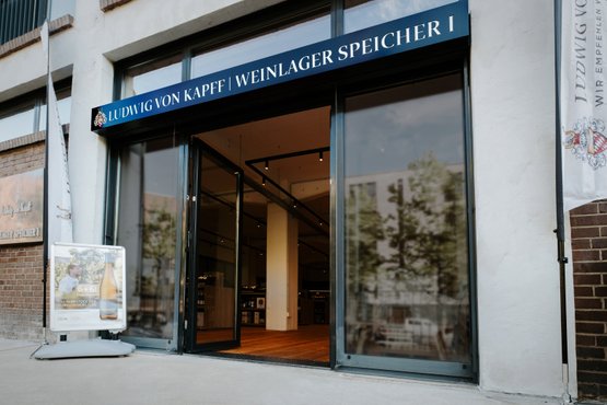 Die Fassade eines Weinlagers mit dem Namen 'Ludwig von Kapff' und einem Werbeschild, das ein Weinangebot bewirbt.